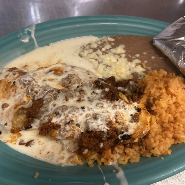 La Fiesta Mexican dish with creamy chicken, rice, refried beans, and cheese on a teal plate.