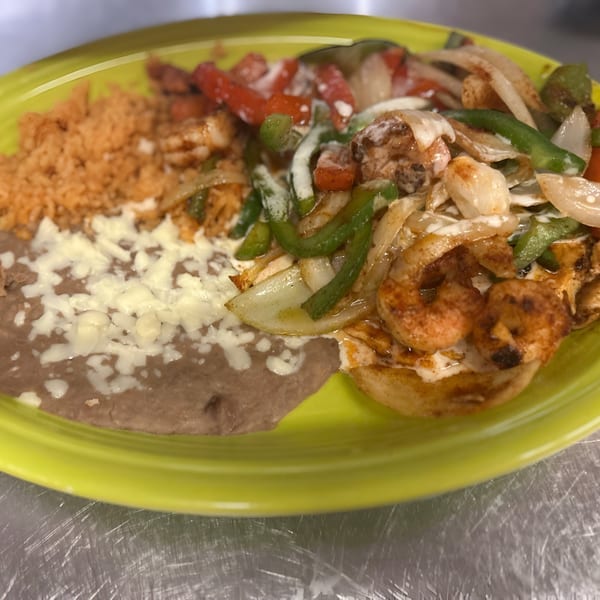 La Fiesta Mexican shrimp fajitas with rice and refried beans on a bright green plate.